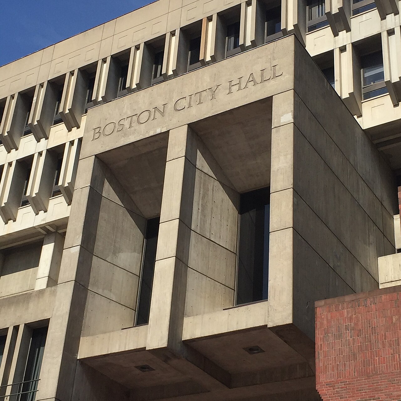 The concrete Brutalist facade of Boston City Hall at Government Center, with the building name engraved above the entrance.