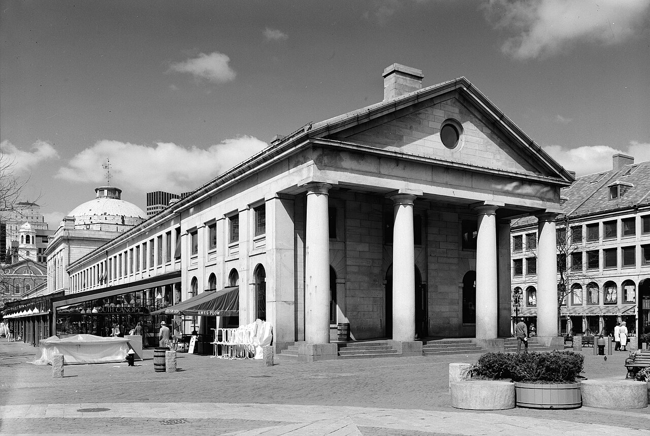 The long granite facade and central dome of Quincy Market behind Faneuil Hall in Boston.